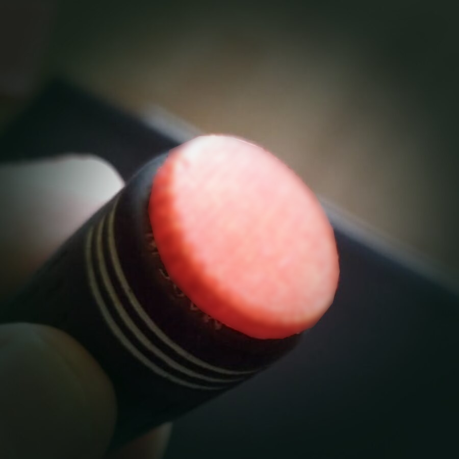 An NFC tag seated in the butt end of a golf club grip, held in one hand